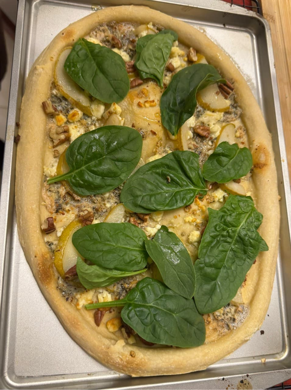 Pizza de pera con queso azul y queso de cabra, adicionada con nuez molida y un t